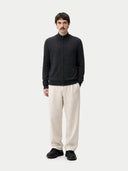 front view of a Man wearing a black zip-up sweater and beige pants on a white background #color_charcoal