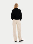 Back view of a person wearing a black sweater and beige pants on a white background #color_black