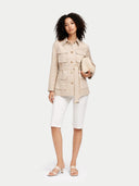Woman wearing a beige jacket and white pants on a light gray background #color_warm-grey