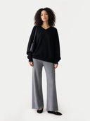 Woman wearing a black sweater and gray checkered pants on a white background #color_dim-gray