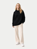 Person wearing a black hoodie and white pants on a white background #color_black