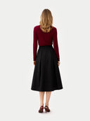Back view of a woman wearing a black skirt and burgundy top on a white background #color_bordeaux