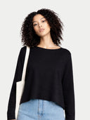 Woman wearing a black sweater and blue jeans against a plain background #color_black