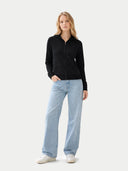 Woman wearing a black jacket and light blue jeans on a white background #color_black