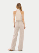 back view of a woman wearing a beige halter top and wide-leg pants on a white background #color_off-white