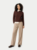 Woman wearing a brown sweater, white shirt, and beige pants on a white background #color_deep-mahogany