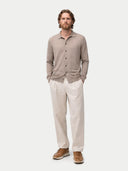 front view of a man wearing a beige button up sweater with a collar and white pants on a white background #color_timber-wolf
