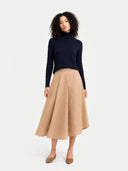front view of a woman wearing a navy turtleneck and beige skirt on a white background #color_navy-blazer
