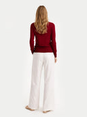 back view of a Person wearing a red sweater and white pants on a white background #color_bordeaux