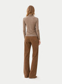 back view of a woman wearing a beige long-sleeve top and brown corduroy pants on a white background #color_taupe