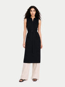 Woman wearing a black sleeveless dress with a belt, standing against a white background #color_black