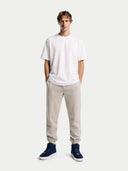 Man wearing a white t-shirt, beige jogger pants, and navy sneakers on a white background #color_navy