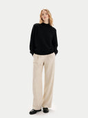 Person wearing a black sweater and beige pants on a white background #color_black