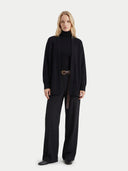 Woman wearing a black cardigan and black pants on a white background #color_black