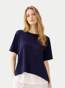 Woman wearing a navy blue top over a white skirt on a light gray background #color_navy