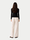 back view of  a black long-sleeve top and white pants on a light gray background #color_black