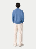 back view of a man wearing a blue sweater and white pants on a light gray background color_blue