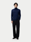 front view of a man wearing a navy turtleneck sweater and black pants on a white background #color_mood-indigo
