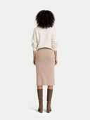 back view of a person wearing a cream sweater and beige skirt with brown knee-high boots on a white background #color_fog