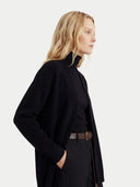 close up of a woman standing sideways wearing a black cardigan and pants on a white background #color_black