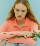 Woman in a pink sweater holding flowers against a light blue background