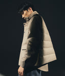 Man wearing a beige puffer vest against a dark background
