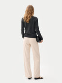 back view of a woman wearing a black top and beige pants on a white background #color_charcoal