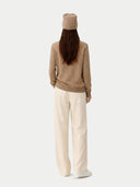 back view of a Person wearing a beige sweater and white pants on a white background #color_taupe
