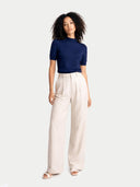 Woman wearing a navy mock top and white pants on a white background #color_mood-indigo