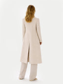 Back view of a person wearing a long beige coat on a white background #color_beige