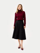 Front-view of a woman wearing a burgundy turtleneck sweater and black skirt on a white background #color_bordeaux