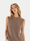 close up of a woman wearing a brown sleeveless knitted sweater against a light background #color_taupe