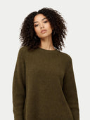 close up of a woman wearing a green sweater against a plain background #color_capulet-olive