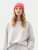 Person wearing a pink beanie and gray sweatshirt on a white background  #color_coral