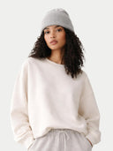 Woman wearing a white sweatshirt and gray beanie on a light gray background #color_high-rise