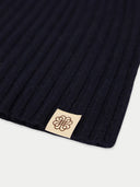 close up of a dark navy ribbed knit fabric with a beige label featuring a logo on a white background  #color_navy-blazer
