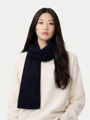 Woman wearing a navy blue scarf and white sweater on a light background #color_peacoat