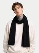 Man wearing a black scarf over a white sweater on a light gray background #color_black