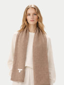 Woman wearing a brown scarf with a visible brand logo on a white background #color_taupe
