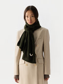 Woman wearing a beige coat and dark green scarf on a white background #color_capulet-olive