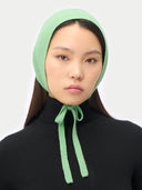 Person wearing a light green knitted bonnet against a white background. #color_zephyr-green
