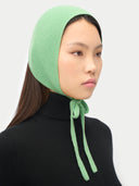 side view of a woman wearing a green knitted bonnet against a white background. #color_zephyr-green