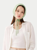 Woman wearing a light green bonnet against a white background #color_zephyr-green