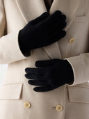 Black gloves being worn over a beige coat with visible buttons. #color_black