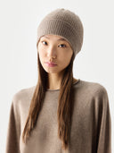 Woman wearing a beige knit beanie and sweater against a white background #color_taupe