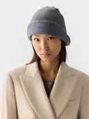 Person wearing a gray knit beanie and beige coat on a white background #color_dim-gray