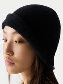 Woman wearing a black knit beanie against a white background #color_black