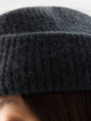 Close-up of a dark gray knit beanie on a neutral background #color_charcaol