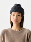 Person wearing a dark gray knit beanie and beige sweater on a white background #color_charcaol