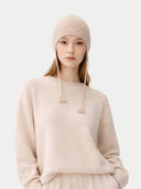 Person wearing a beige knit hat and sweater on a white background #color_beige
